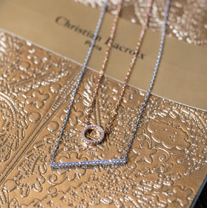 white gold vertical bar necklace and to infinity and beyond necklace on a book